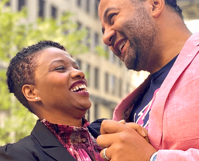 Man and woman smiling from below wearing pink